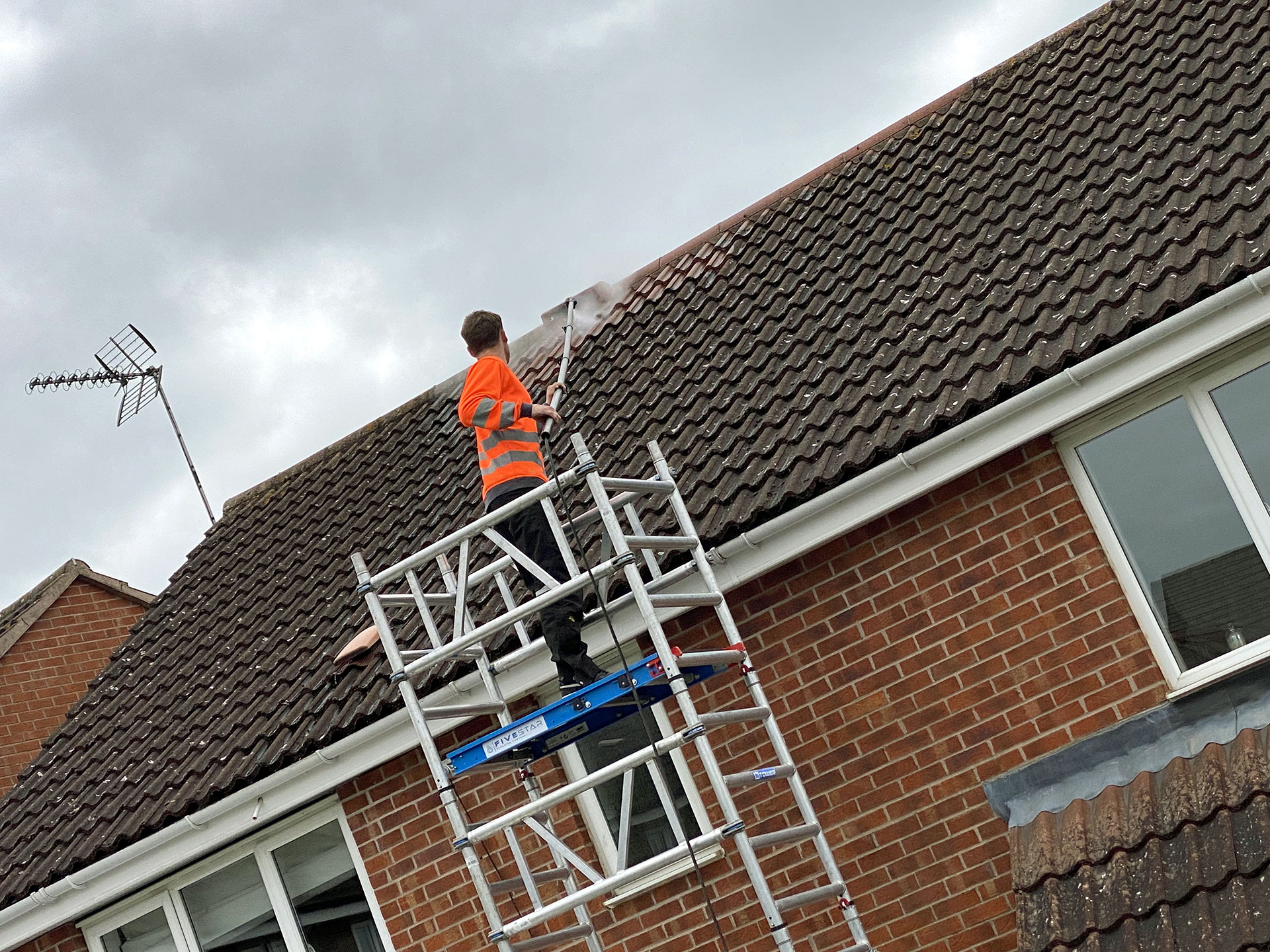 Person cleaning the roof of a house